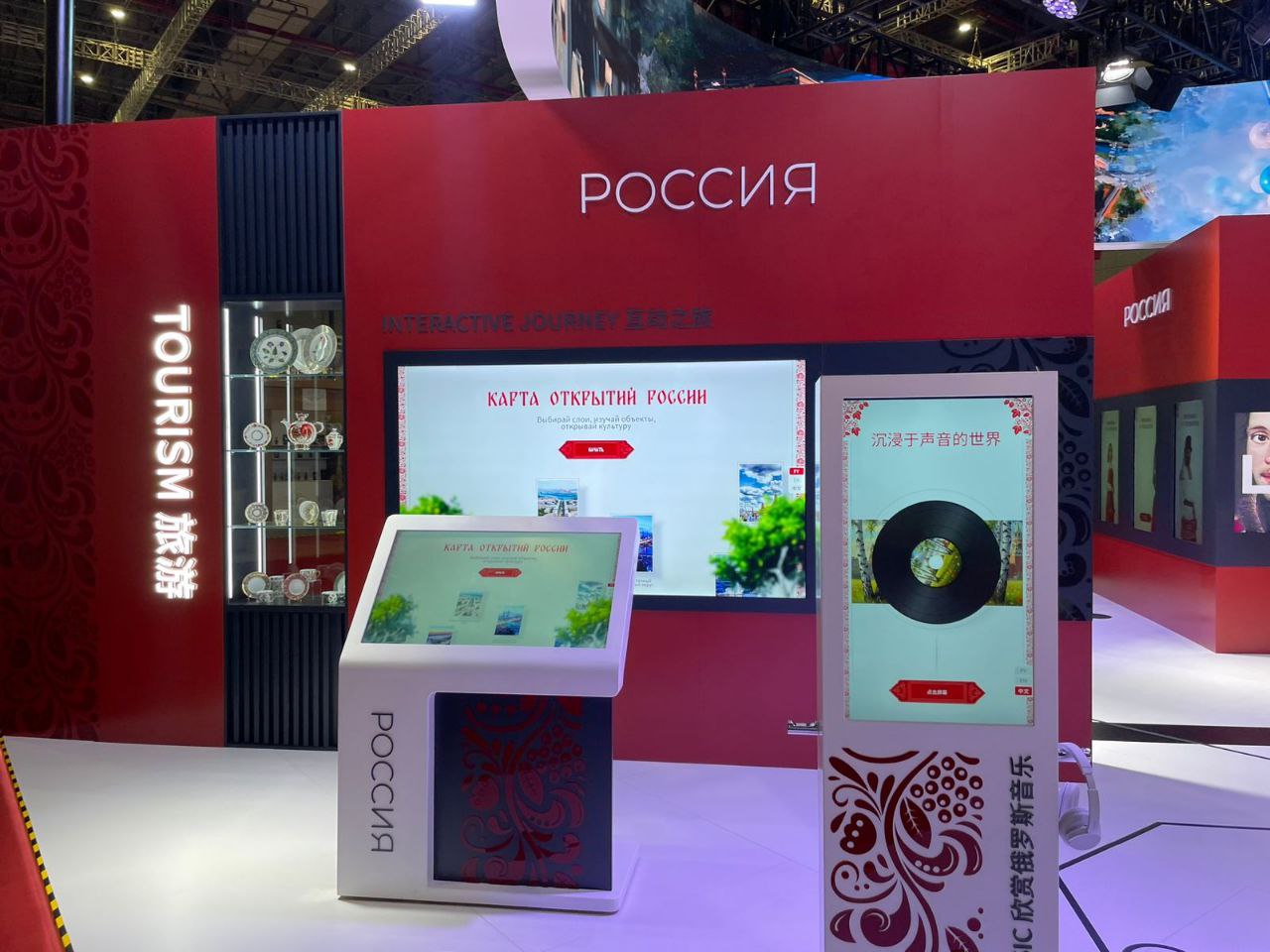 «Карта открытий России» на русском языке: сенсорный киоск и настенный экран, рядом музыкальная стойка с пластинкой на экране