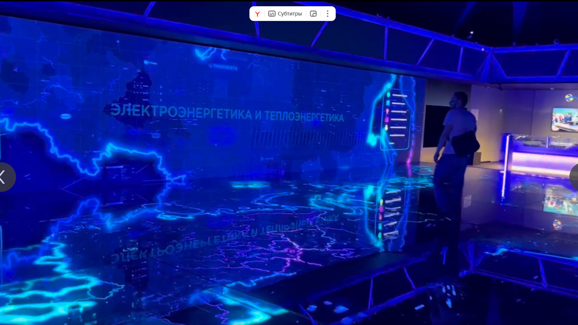 A visitor at a blue LED map wall with the words “Electric power and heat power”