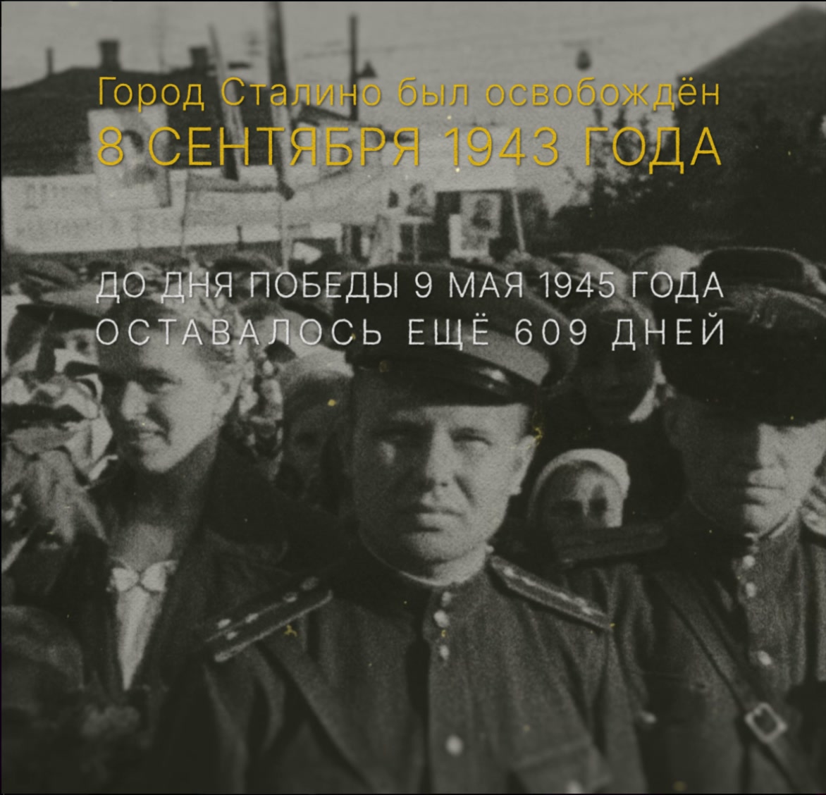 Кадр проекции «Освобождение Сталино»: надпись «Город Сталино был освобождён 8 сентября 1943 года» поверх кинохроники с жителями и военными