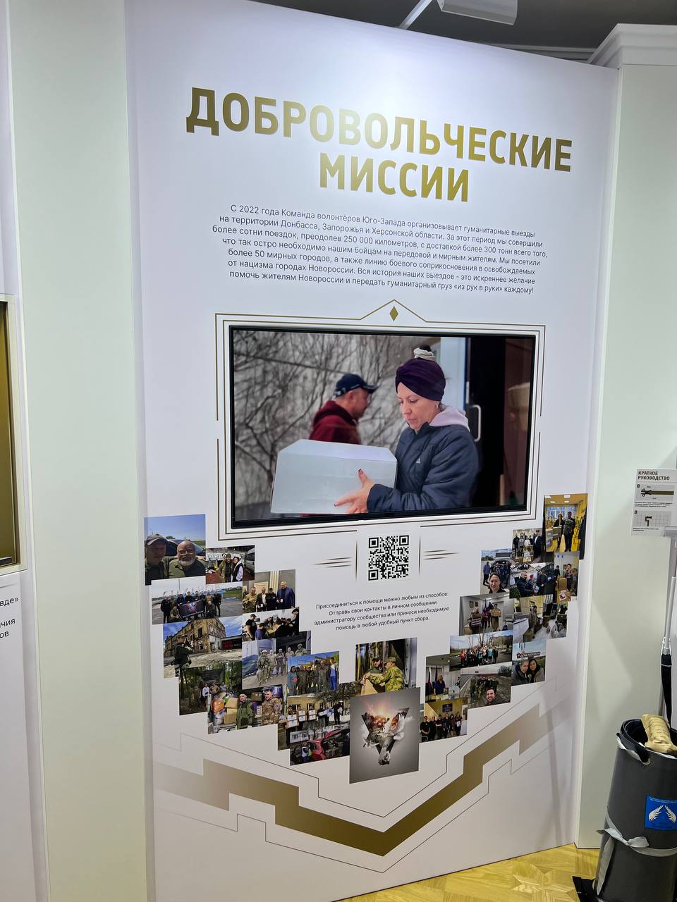 “Volunteer missions” stand: text about the South-West Volunteer Team, a screen showing a still from the video — volunteers handing over a box — and below, a QR code and a collage of photographs from the trips