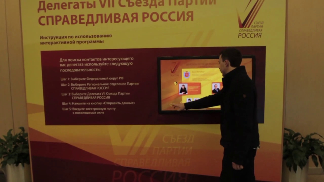 Мужчина у сенсорного киоска на стенде «Делегаты VII съезда Партии СПРАВЕДЛИВАЯ РОССИЯ» с инструкцией