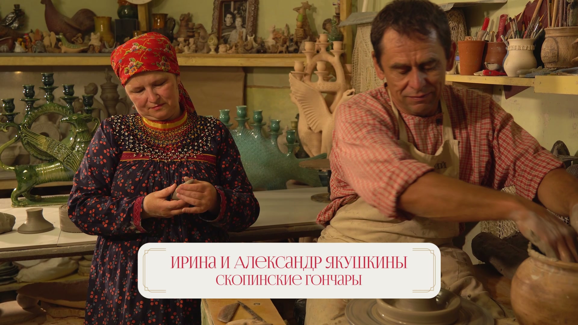 Кадр ролика: Ирина и Александр Якушкины в гончарной мастерской, за ними — полки с керамикой