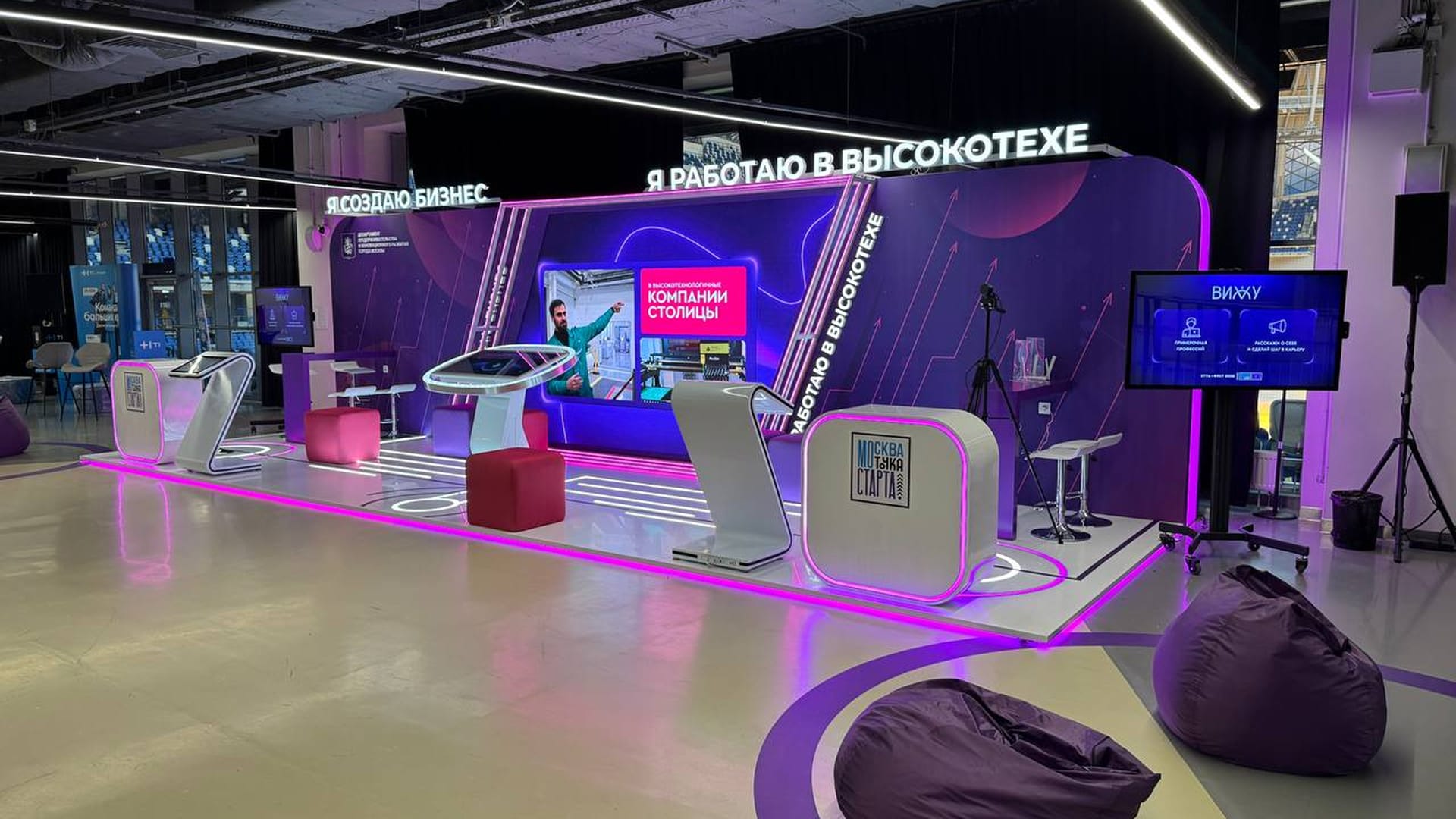 The stand from the right: a camera on a tripod, kiosks and a touch table