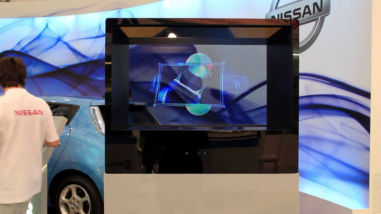 Голографический куб с логотипом Nissan на стойке рядом с голубым электромобилем