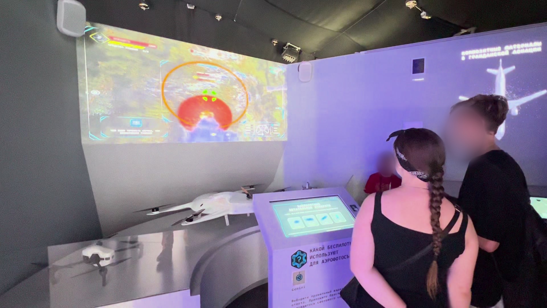 Visitors at a large projection with a drone game in the “Aviation hangar” of the “Made by us” pavilion of the Ministry of Industry and Trade