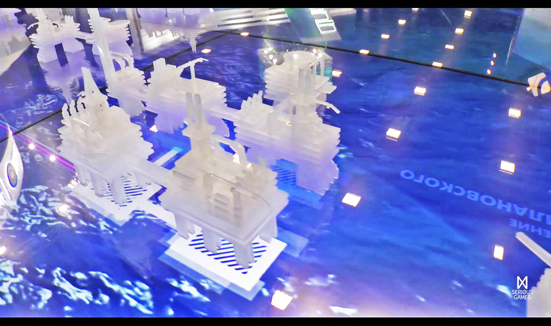 Белые полупрозрачные макеты морских платформ, соединённых мостами, на синем экране с подсвеченными площадками