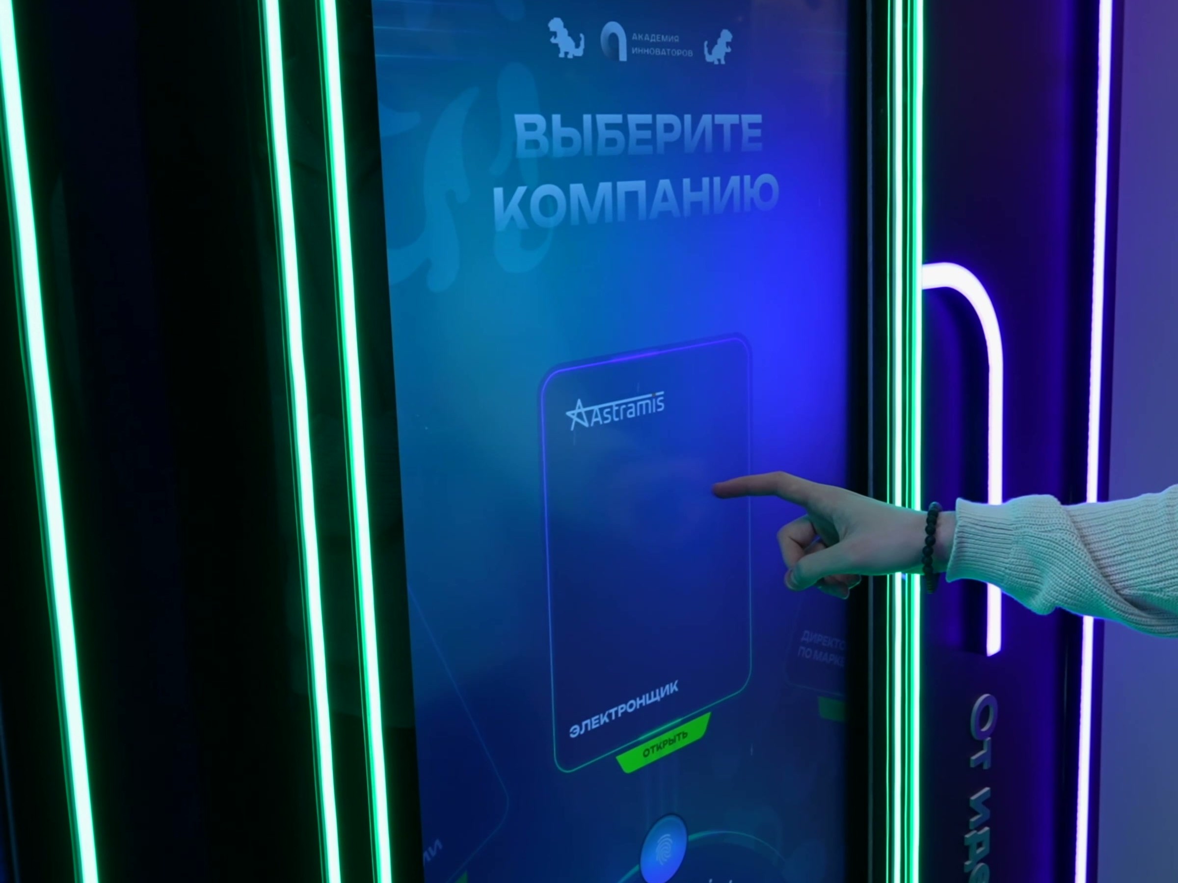 Посетитель нажимает на карточку стажировки «Электронщик» на вертикальном сенсорном экране «Выберите компанию»