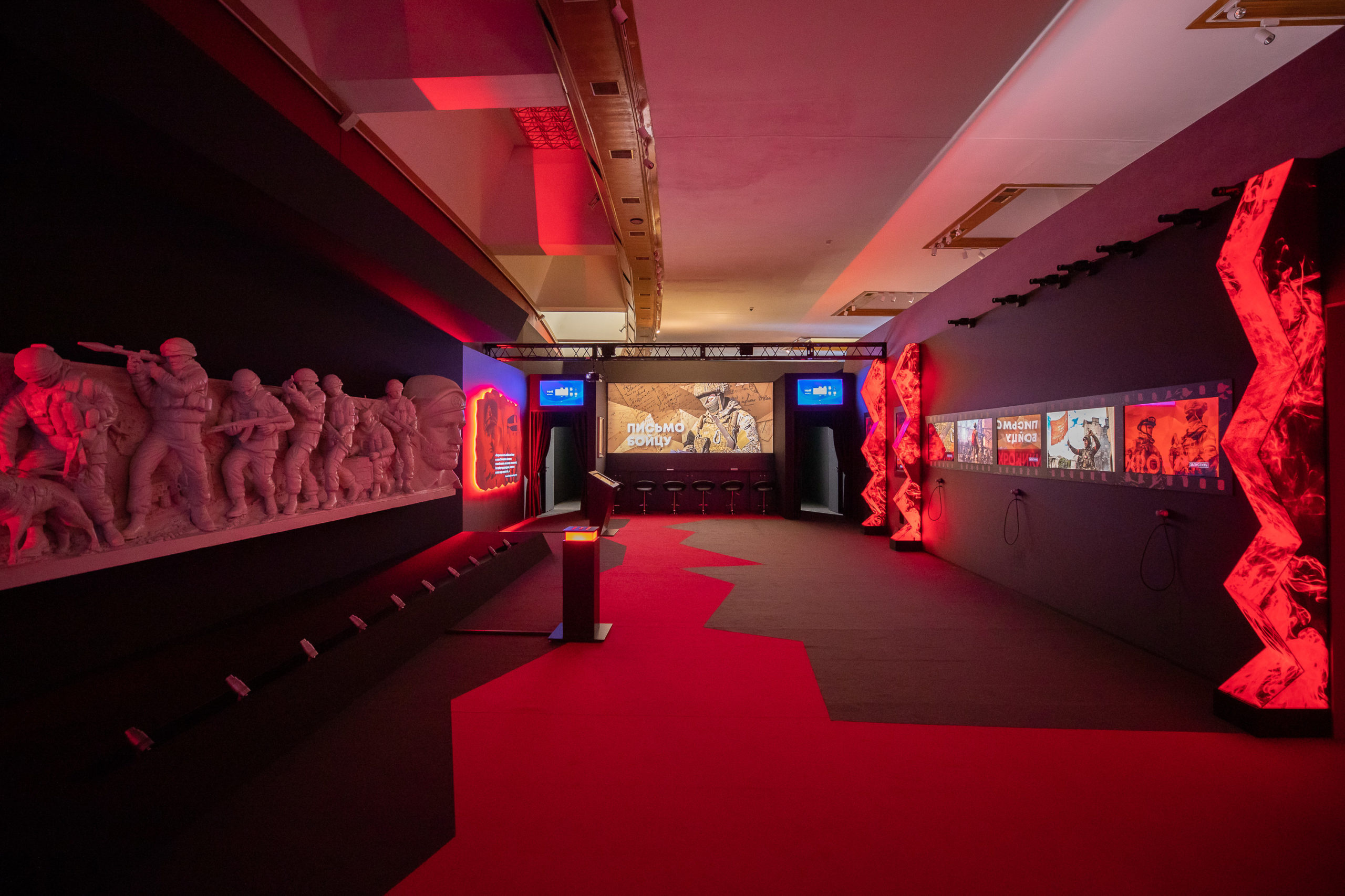 General view of the exhibition: on the left, a copy of the “Saur-Mogila” bas-relief; in the background, the projection and the “Parallels morphing” stand; on the right, walls with light zigzags into which the “Parallels” screens are built